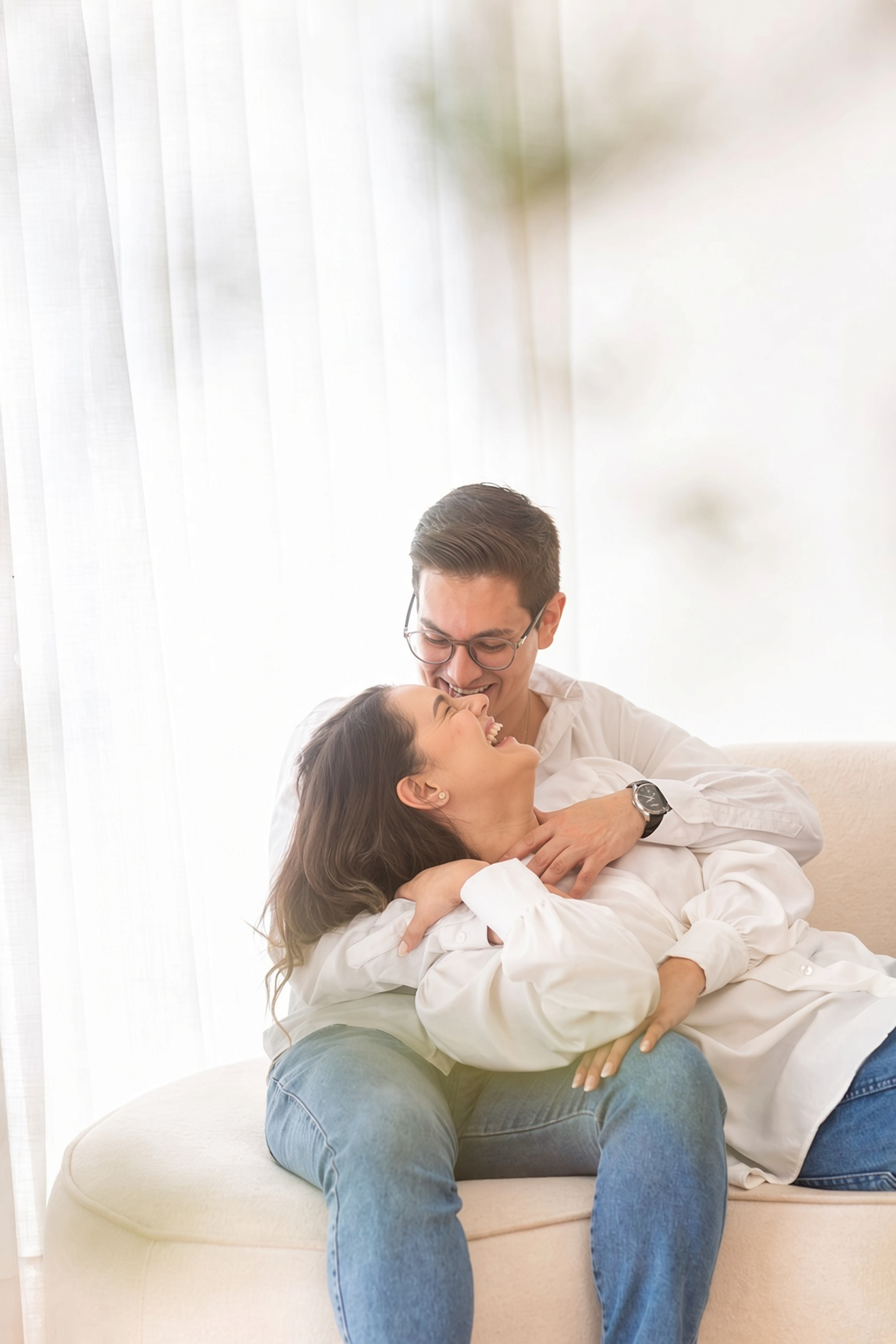 Maria e Thiago rindo juntos no sofá