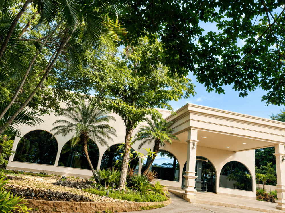 Entrada do Buffet Luzes e Jardins entre árvores e jardins